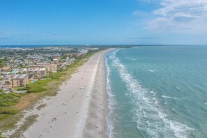 Un paisaje urbano costero con una playa extensa, edificios y cielo despejado.