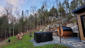 Un espace extérieur boisé, avec un sentier en pierre, un chauffage d’extérieur noir et un tonneau en bois.