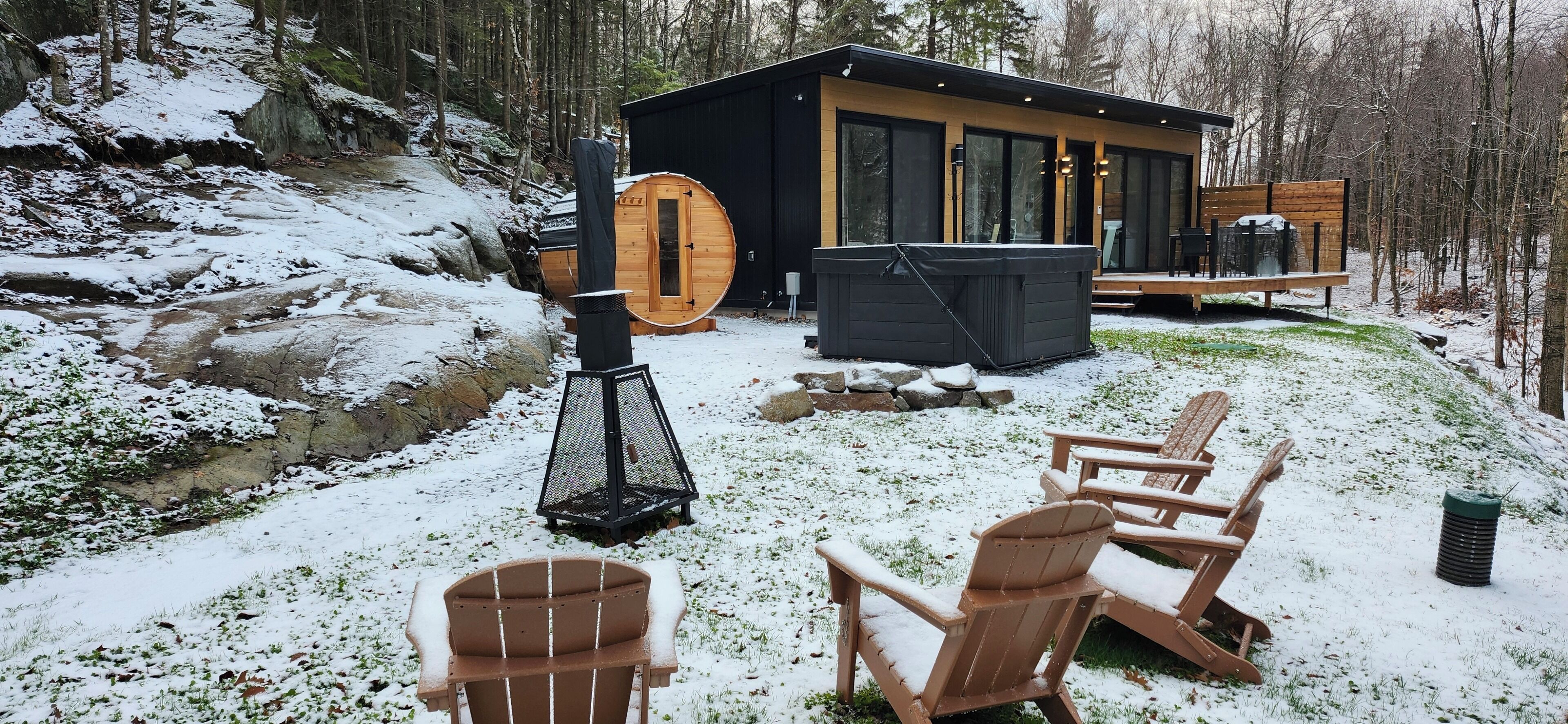 Una cabaña con jacuzzi, terraza de madera y mobiliario exterior.
