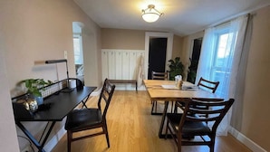 Un comedor con una mesa y sillas de madera, un radiador y una ventana con cortinas.
