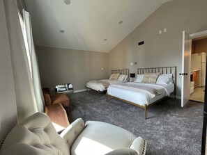 A bedroom with two beds, a sofa, and a small table. - Nori’s Nook Downtown Grand Forks (Grand Forks)