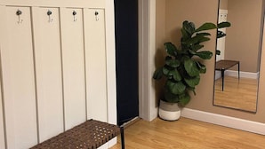 Una habitación con un banco, una planta en maceta, un espejo y una puerta.