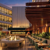 An outdoor dining area with a bar, a fountain, and a building with 'ATRIUM' signage.