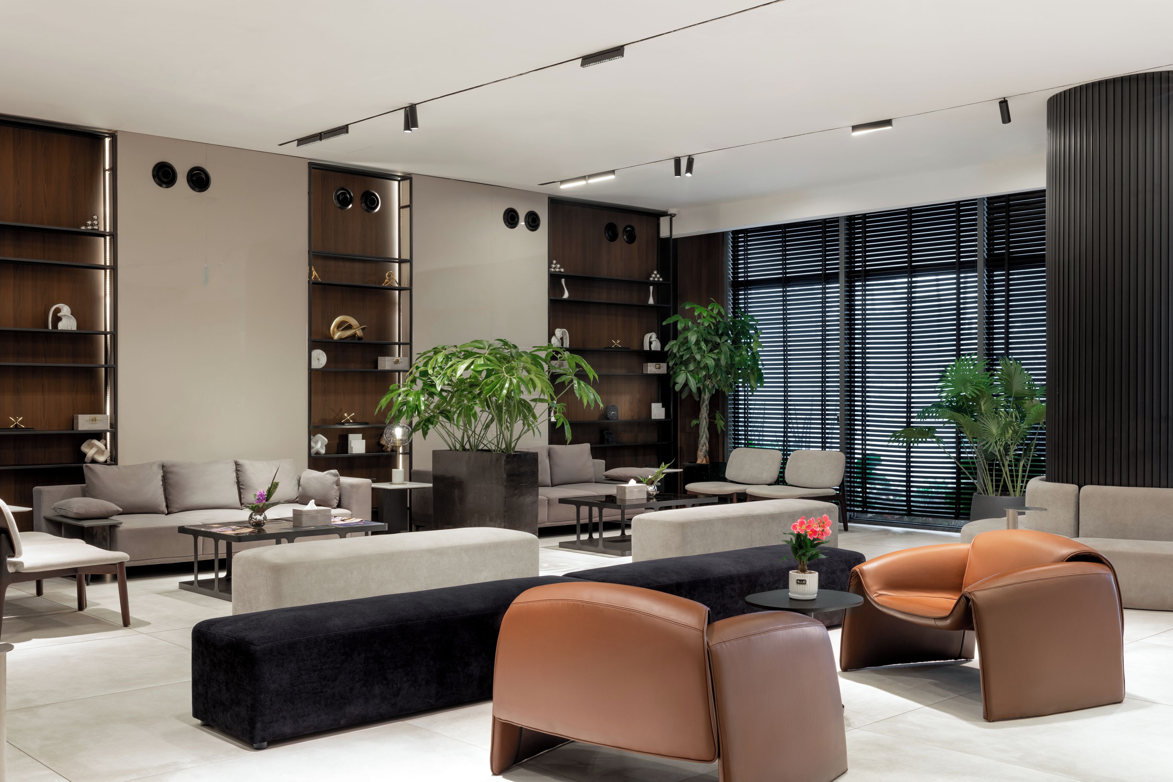 A modern living room with a sofa, armchairs, a coffee table, and a large window with blinds.