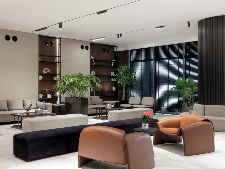 Una sala de estar moderna con un sofá, sillones, una mesa de centro y un ventanal con persianas.