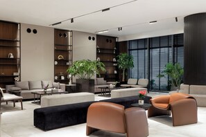 Una sala de estar moderna con un sofá, sillones, una mesa de centro y un ventanal con persianas.