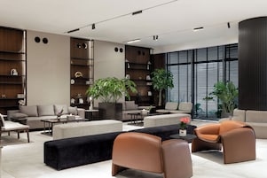 A modern living room with a sofa, armchairs, a coffee table, and a large window with blinds.