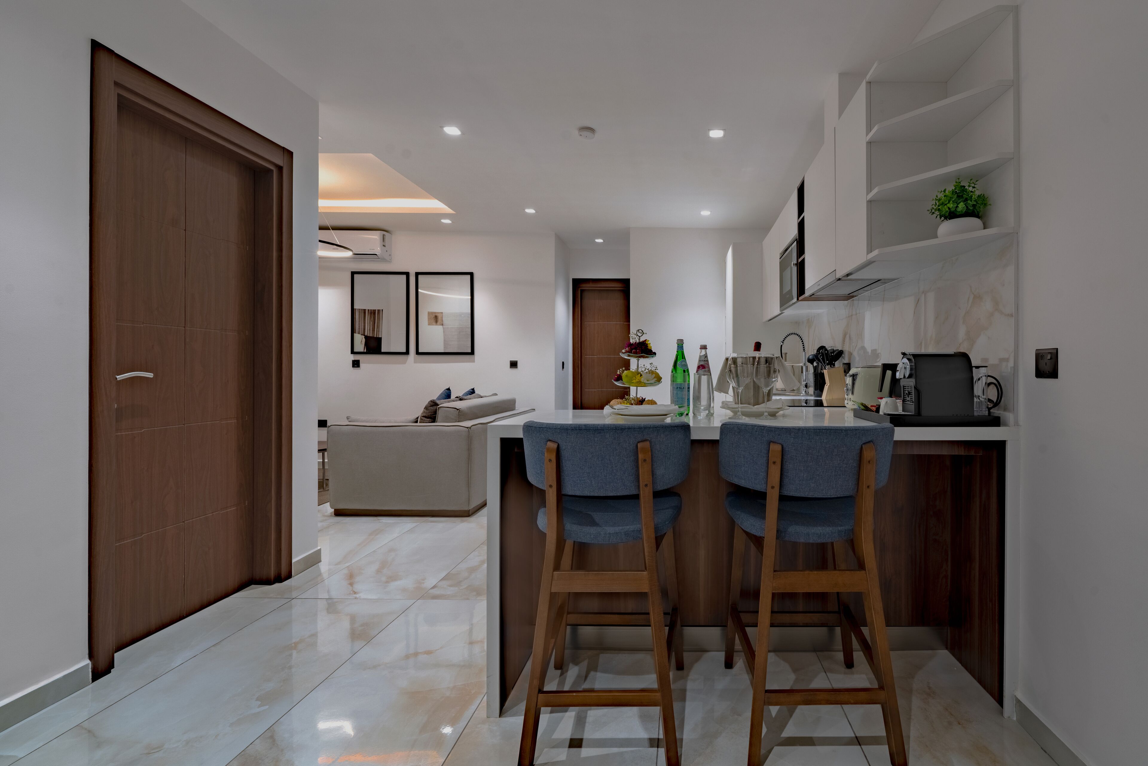 A modern kitchen with a central island, wooden chairs, and a dining table.
