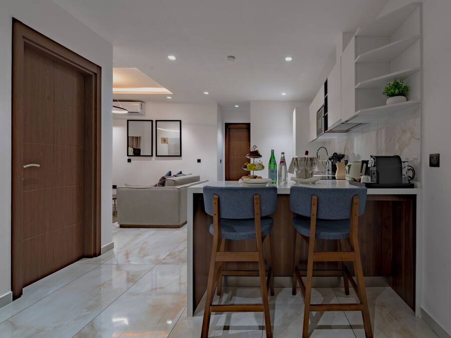A modern kitchen with a central island, wooden chairs, and a dining table.