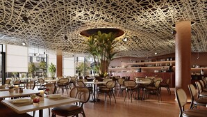 Un interior de restaurante moderno con un diseño de techo único, varias zonas de estar y una barra visible al fondo.