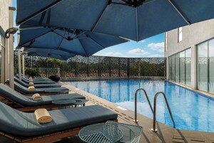 A poolside area with sun loungers and umbrellas, a clear sky, and a pool.