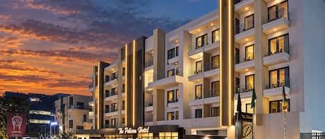 A modern hotel with multiple balconies and a well-lit entrance.