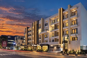 Un hôtel moderne doté de nombreux balcons et d’une entrée bien éclairée.