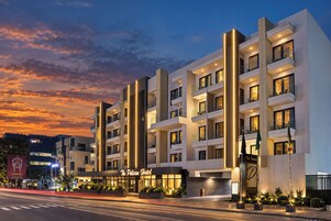 A modern hotel with multiple balconies and a well-lit entrance.