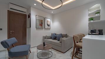 Uma sala de estar moderna com um sofá, uma mesa de centro e um espaço de jantar com cadeiras.