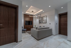A modern living room with a sofa, a TV, and a wooden wardrobe.
