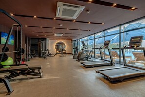 Un gimnasio moderno con cintas de correr, máquinas de pesas y pelotas de ejercicio.