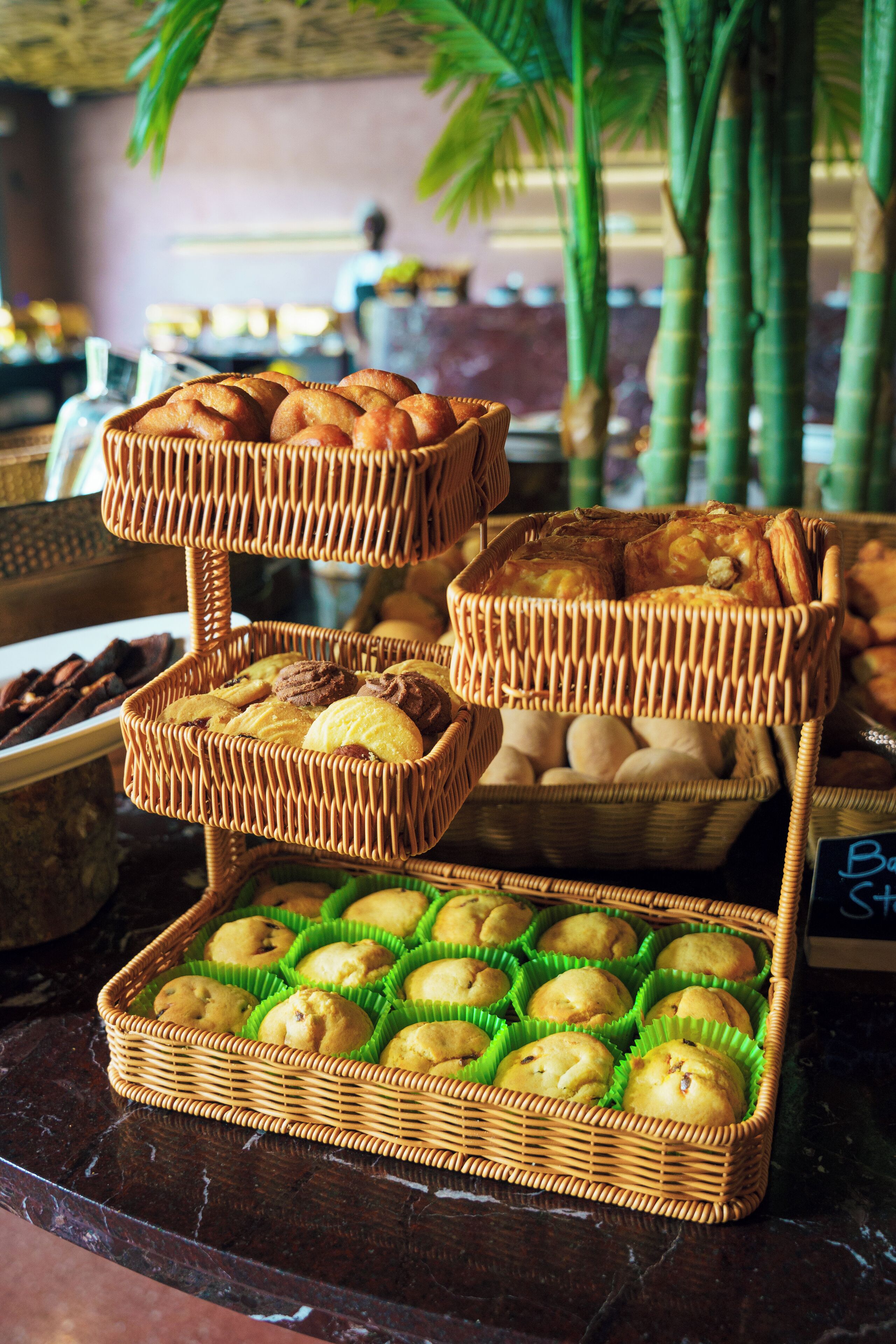A buffet with various baked goods displayed in wicker baskets.
