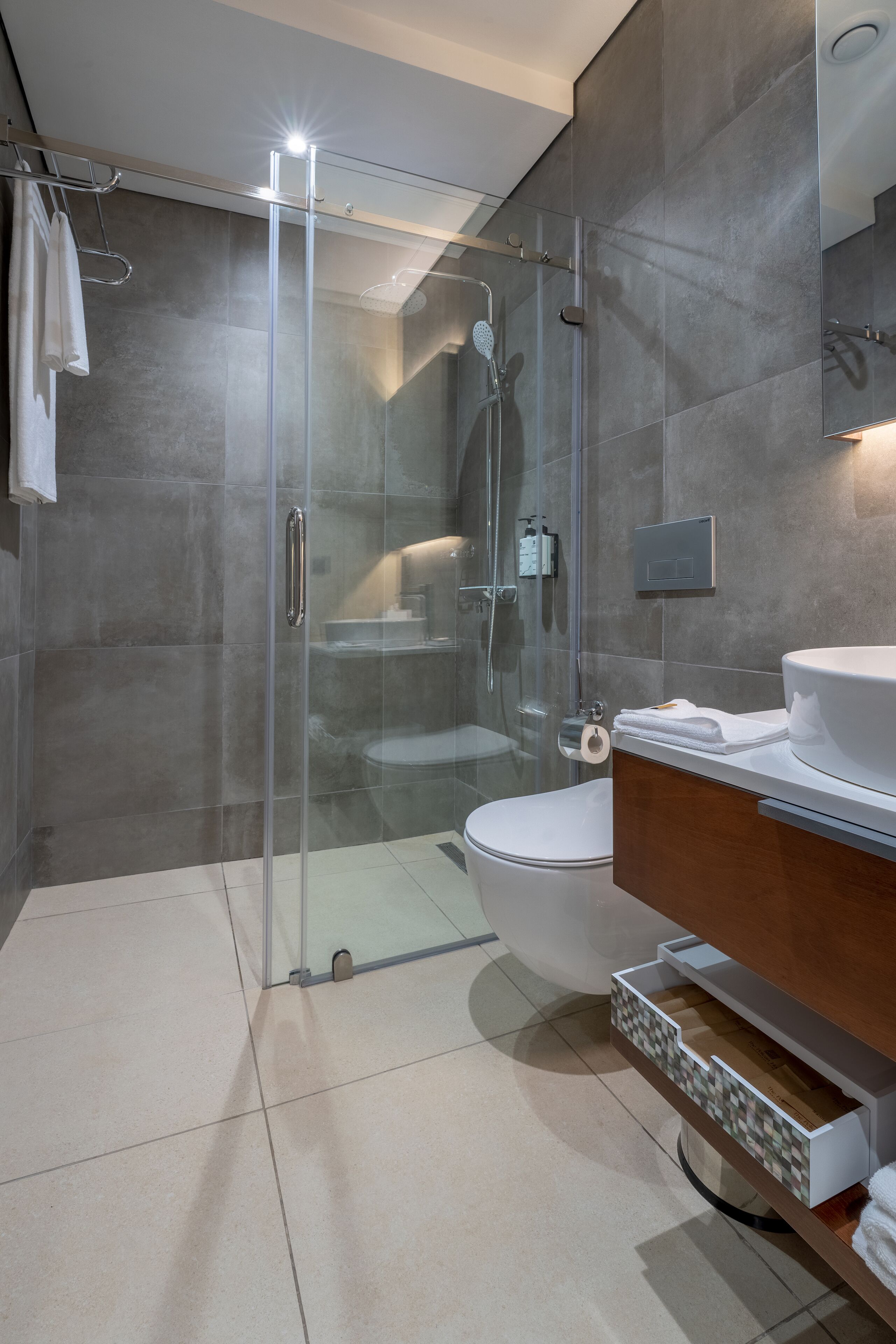 A modern bathroom with a glass-enclosed shower, a toilet, and a vanity with a sink and mirror.