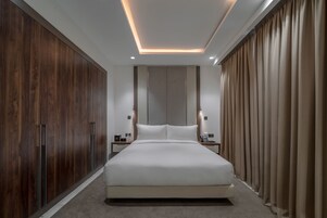 A modern bedroom with a large bed, wooden wardrobe, and a neutral color scheme.