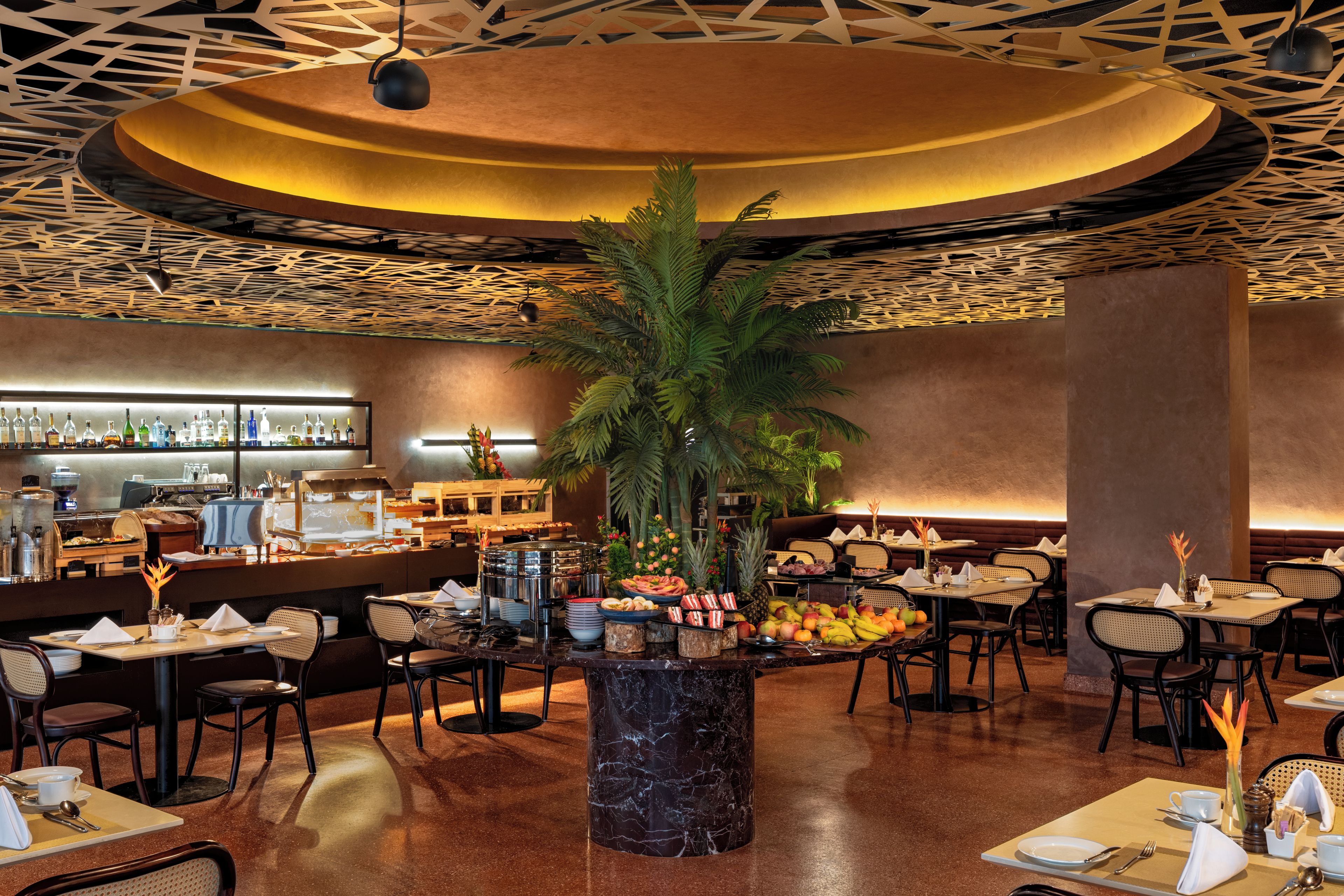 A restaurant with a central island featuring a plant, surrounded by tables and chairs.