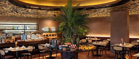 A restaurant with a central island featuring a plant, surrounded by tables and chairs.
