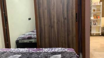 Un dormitorio con una cama, un armario de madera y una estantería al fondo.