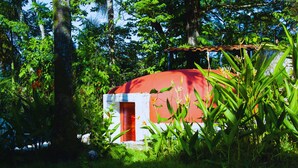 Um edifício vermelho e branco cercado por vegetação exuberante.