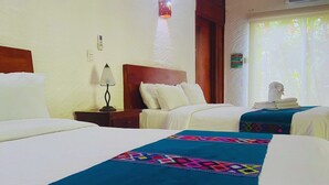 Quarto de hotel com duas camas, mesa de cabeceira, abajur e janela com cortinas.