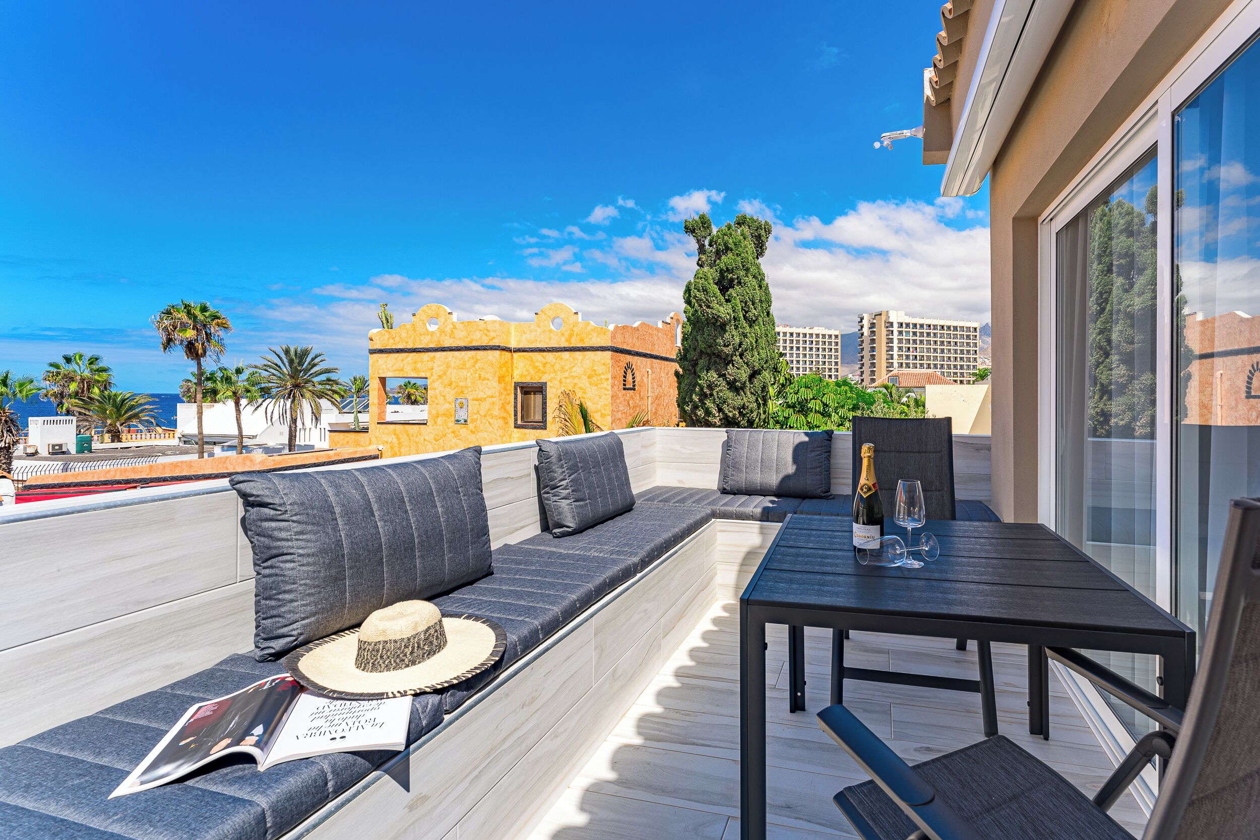 Eine Dachterrasse mit Sitzgelegenheit, Tisch und einer Champagnerflasche.