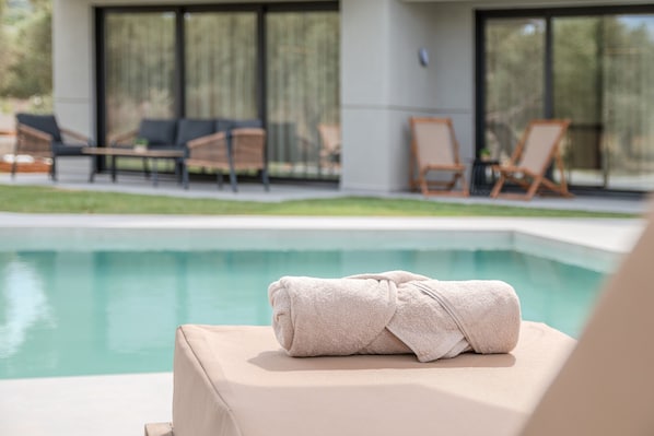 A poolside area with lounge chairs and a towel on a chair.