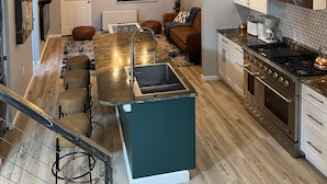 Ett modernt kök med en central köksö, rostfria vitvaror och en matplats med soffa och stolar.