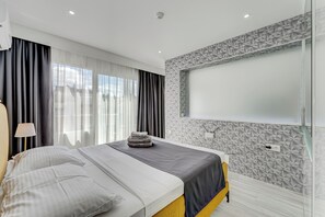 Relax in a spacious room with a large bed, wall-mounted TV, and geometric patterned wall.