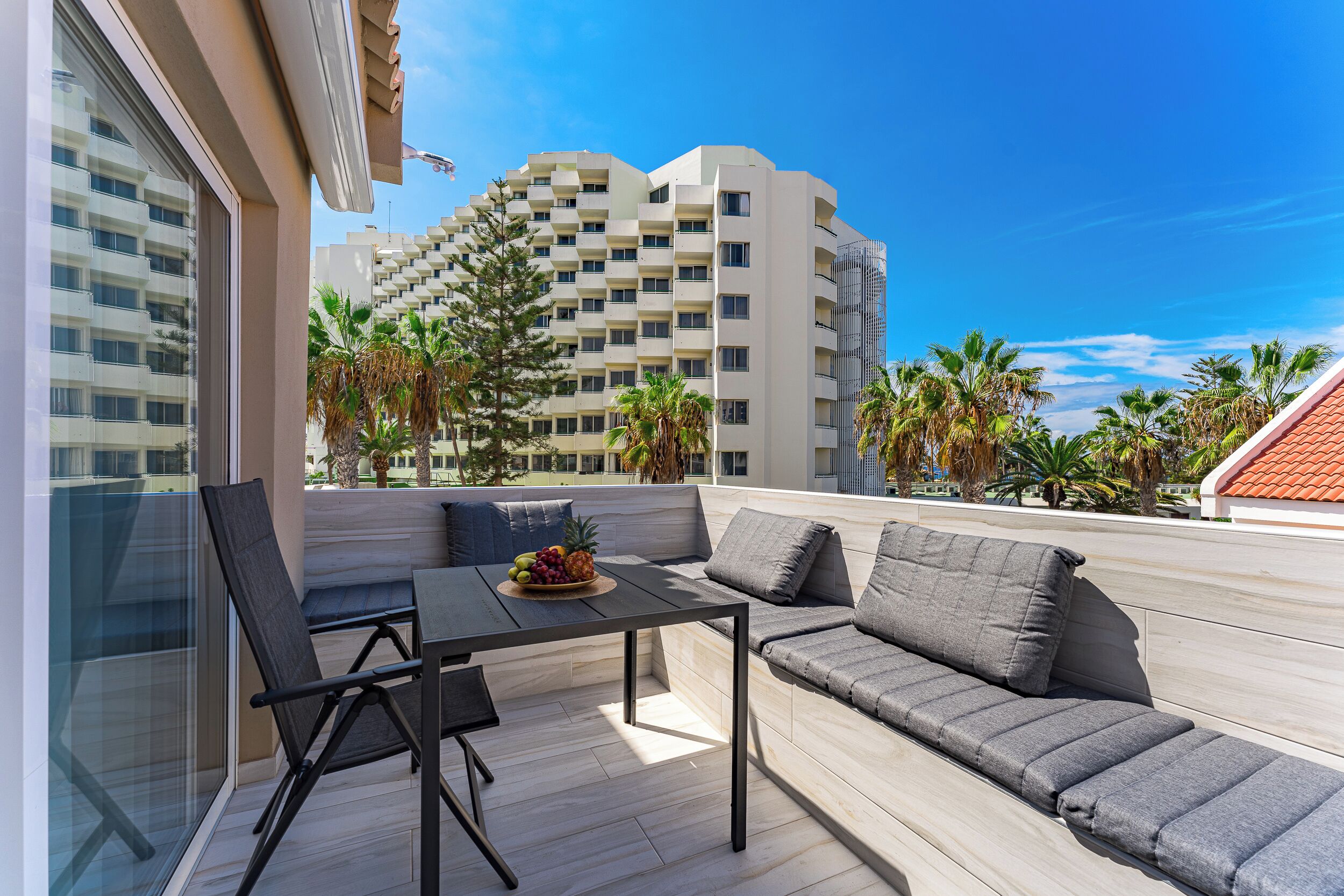 A balcony with a table, chairs, and a sofa.