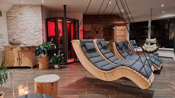 Ein moderner Loungesessel mit einer gebogenen Couch und einem Hängesessel, einem Holzschrank und Topfpflanzen.