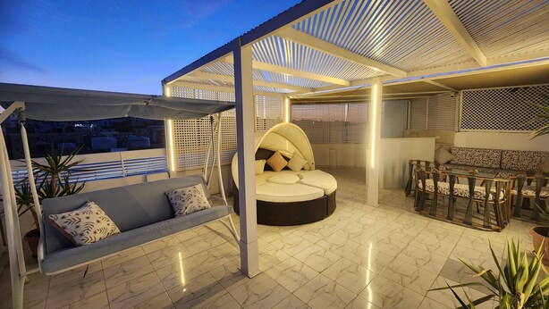 A rooftop terrace with a cushioned seating area, a swing, and a dining set. - White Roof - Hurghada (Hurghada)