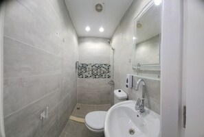 Un baño con inodoro, lavamanos y ducha.