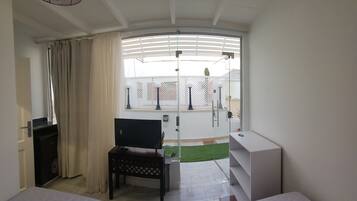 A hotel room with two beds, a desk, a TV, and a balcony with a view.