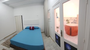 A room with a bed, a wardrobe, and a view of a balcony with a round table and chairs. - White Roof - Hurghada (Hurghada)