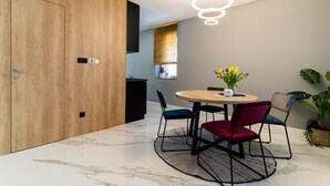 A modern dining area with a round table, chairs, and a potted plant.