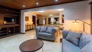 Una sala de estar con sofá, televisor, comedor y escalera.