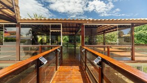Un pasillo cubierto de madera con barandillas de vidrio que conduce a un edificio con tejado de baldosas.