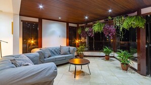 Un área de estar moderna con un sofá, una mesa redonda y plantas en macetas.