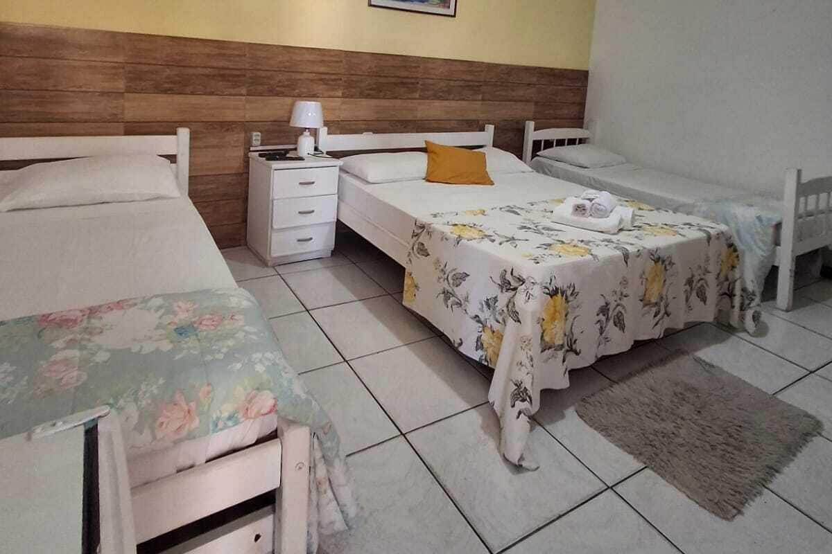 A bedroom with two single beds, a nightstand, a bedside table, a ceiling fan, and a painting on the wall.