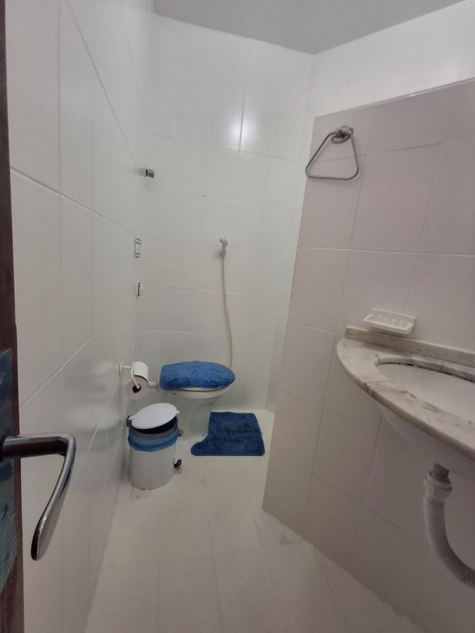 Un baño pequeño y funcional con azulejos blancos, un inodoro, un bidé y un lavamanos.