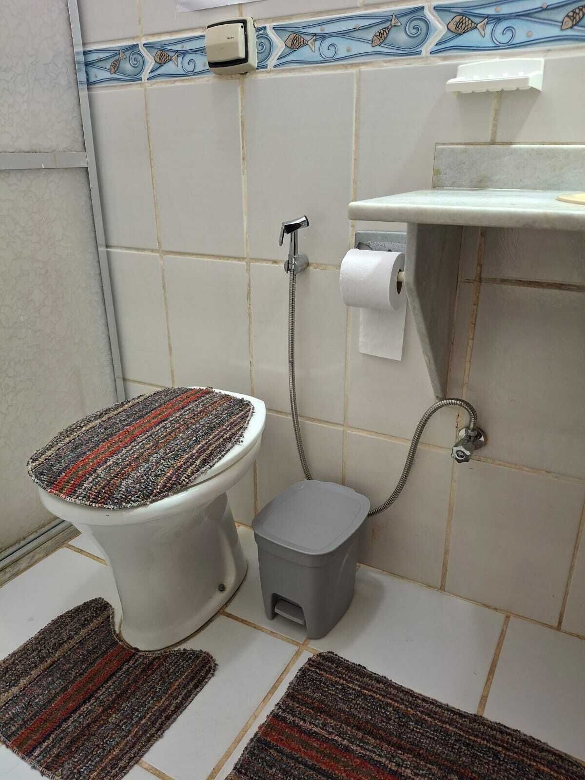 Un bagno con un water, una doccia e un piccolo cestino.