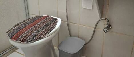 Un bagno con un water, una doccia e un piccolo cestino.