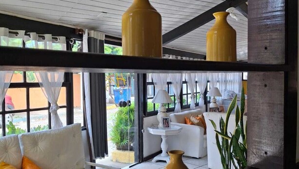 Een modern interieur met een witte bank, gele vazen en uitzicht op buiten.