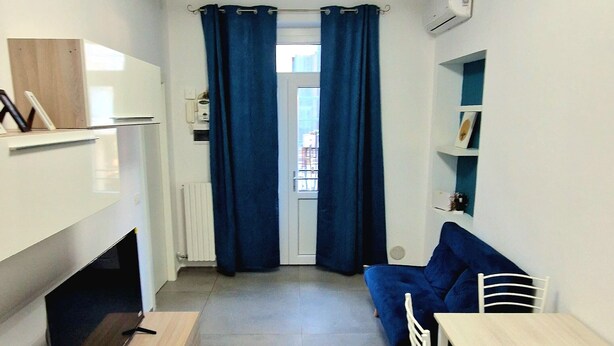 A compact room with a bed, a desk, a chair, and a window with curtains.
