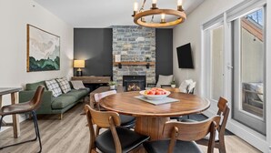 Un salon moderne avec une cheminée en pierre, une table de salle à manger ronde en bois et des sièges confortables.